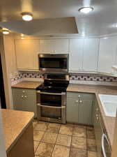 Kitchen featuring decorative backsplash, white cabinetry, and stainless steel appliances