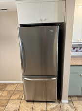 Details with white cabinetry, tasteful backsplash, and stainless steel fridge