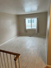 Den at top of stairs featuring light wood-type flooring and a textured ceiling