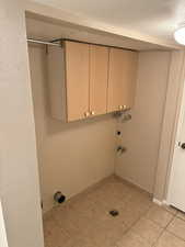 Washroom featuring cabinets, light tile patterned floors, and a textured ceiling