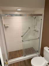 Master bathroom featuring hardwood / wood-style floors, toilet, and a shower with shower door