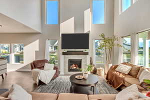 Living room featuring a wealth of natural light, a high ceiling, and a fireplace