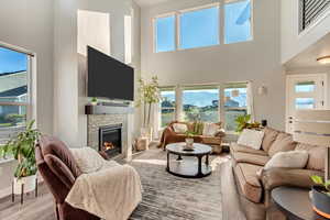 Living room featuring a high ceiling, a fireplace, mountain views, and an abundance of natural light.