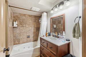 Bathroom with shower / tub combo with curtain, a textured ceiling, and vanity