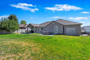 Back of house with a lawn, a hot tub, and a patio