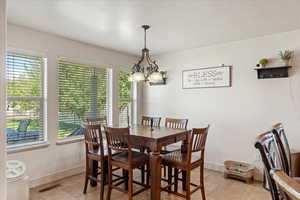 Dining space featuring a chandelier, a textured ceiling, and light tile patterned floors