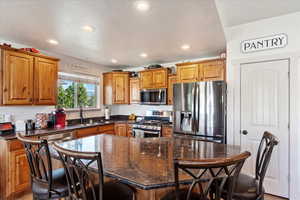 Kitchen featuring a textured ceiling, appliances with stainless steel finishes, a breakfast bar, and a kitchen island