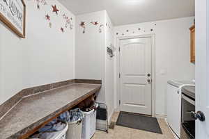 Washroom featuring light tile patterned floors, cabinets, washer and dryer, and a textured ceiling