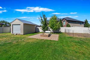 View of yard with a storage shed, an outdoor fire pit, and a patio area