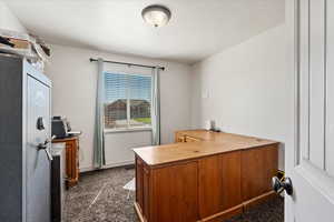 Carpeted home office with a textured ceiling