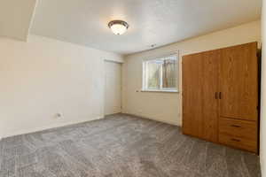 Unfurnished bedroom with a textured ceiling and carpet