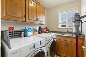 Laundry room with sink, washer and dryer, and cabinets