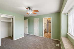 Unfurnished bedroom with multiple windows, light carpet, ensuite bath, and ceiling fan