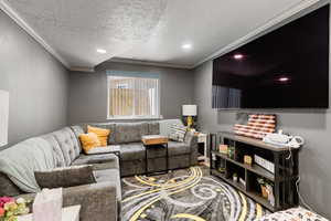 Living room with ornamental molding and a textured ceiling