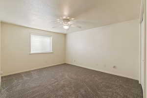 Carpeted spare room featuring a textured ceiling and ceiling fan