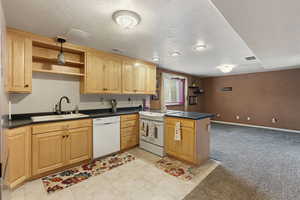 Kitchen with kitchen peninsula, sink, white appliances, a textured ceiling, and light carpet