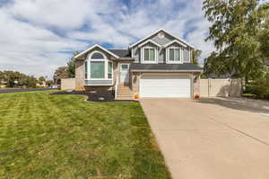 View of front of property with a garage and a front lawn