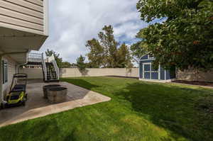 View of yard with a wooden deck, a patio, a shed, and a fire pit