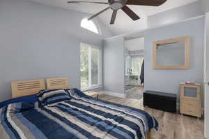 Bedroom featuring light hardwood / wood-style flooring, connected bathroom, multiple windows, and ceiling fan