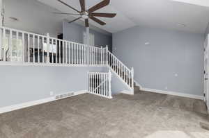 Interior space with ceiling fan, vaulted ceiling, and carpet flooring