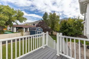 Wooden terrace with a mountain view, a lawn, and a storage unit