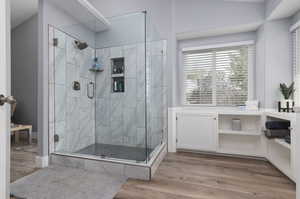 Bathroom featuring hardwood / wood-style flooring and a shower with shower door