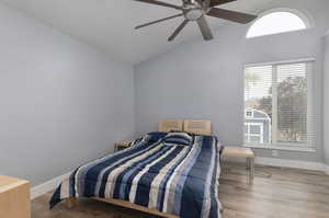 Bedroom with lofted ceiling, ceiling fan, and hardwood / wood-style flooring