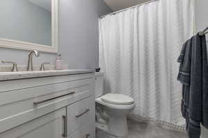 Bathroom featuring vanity, tile patterned flooring, toilet, and curtained shower