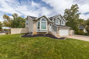 View of front facade featuring a garage and a front lawn