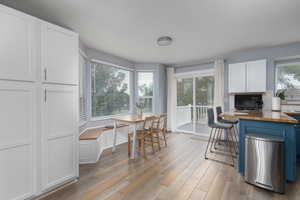 Kitchen featuring white cabinets, light wood-type flooring, wooden counters, and a healthy amount of sunlight