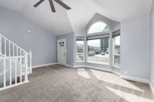 Unfurnished living room with carpet floors, ceiling fan, and high vaulted ceiling