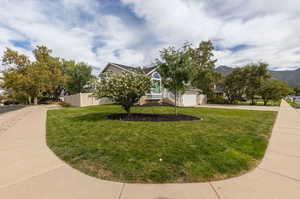 View of front of home with a mountain view, a garage, and a front lawn