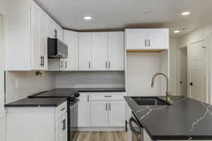 Kitchen with appliances with stainless steel finishes, sink, and white cabinets