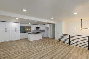 Kitchen featuring a chandelier, sink, white cabinetry, hanging light fixtures, and light hardwood / wood-style flooring