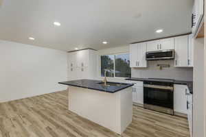 Kitchen featuring an island with sink, stainless steel appliances, light hardwood / wood-style floors, and sink