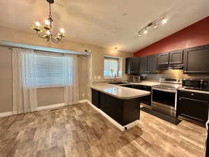 Kitchen featuring stainless steel appliances.  Newer oven.  Breakfast bar.  Chandelier.  Vaulted ceiling.  Laminate flooring.