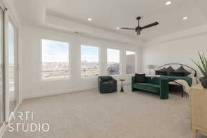 Carpeted bedroom with ceiling fan and a tray ceiling