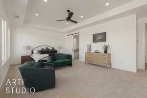 Carpeted bedroom featuring ensuite bathroom, a raised ceiling, ceiling fan, and a barn door