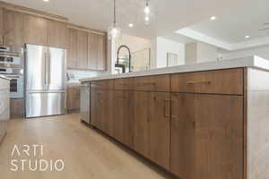 Kitchen featuring decorative light fixtures, decorative backsplash, light wood-type flooring, appliances with stainless steel finishes, and sink