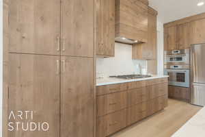 Kitchen with stainless steel appliances, custom exhaust hood, light hardwood / wood-style flooring, and tasteful backsplash