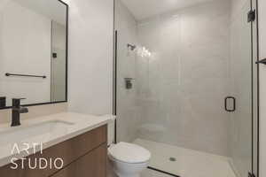 Bathroom with toilet, vanity, and a shower with shower door