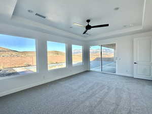 Unfurnished room with ceiling fan, carpet flooring, and a raised ceiling