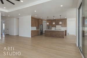 Kitchen featuring decorative light fixtures, a center island with sink, stainless steel appliances, light hardwood / wood-style floors, and decorative backsplash