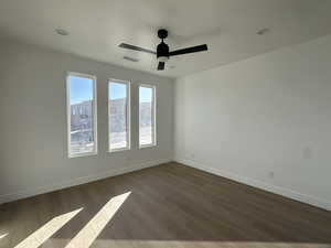 Empty room with dark hardwood / wood-style floors and ceiling fan