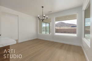 Unfurnished dining area with a mountain view, a chandelier, and light hardwood / wood-style flooring