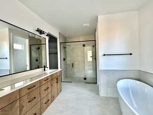 Bathroom with tile patterned flooring, plus walk in shower, tile walls, and vanity