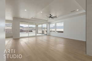 Empty room featuring a raised ceiling, a mountain view, plenty of natural light, and hardwood / wood-style floors