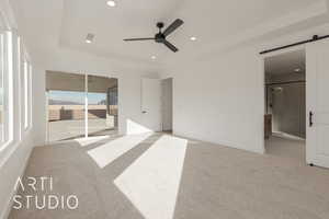 Unfurnished bedroom with connected bathroom, access to exterior, ceiling fan, a barn door, and light carpet