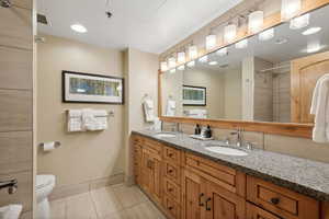 Bathroom with a tile shower, vanity, toilet, and tile patterned floors