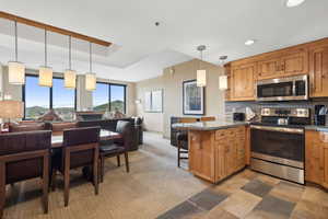 Kitchen with appliances with stainless steel finishes, hanging light fixtures, tasteful backsplash, kitchen peninsula, and a kitchen bar